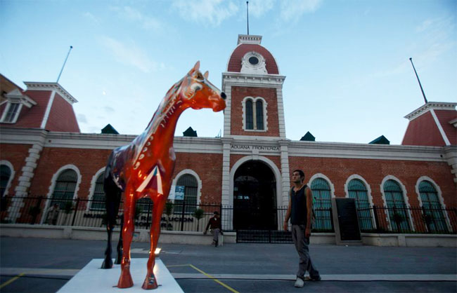 游客近距离观察一具玻璃纤维马雕塑